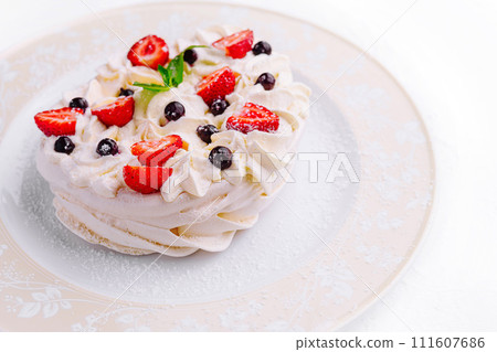 Pavlova cakes with cream and fresh berries on plate 111607686