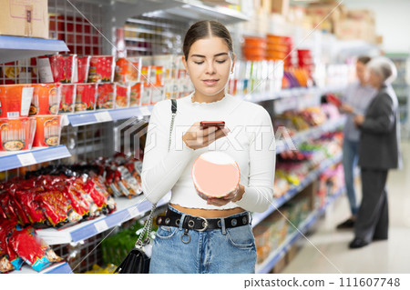 Young woman in supermarket scan QR code on instant fast food package Young woman in supermarket scan QR code on instant fast food package 111607748