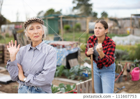 Two angry casual women neighbors of different ages arguing during the vegetable garden season on sunny day of spring 111607753