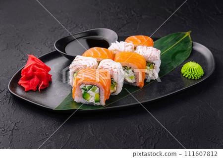 sushi rolls with salmon and crab on black plate 111607812
