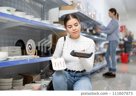 Young girl choosing square plates for serving sushi in Asian store 111607873