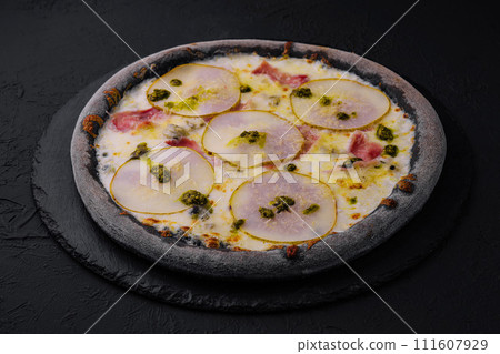 black pizza with pear, cheese and ham 111607929