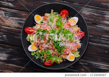 Salad with salmon, lettuce, boiled eggs, cherry tomatoes and parmesan cheese 111608087