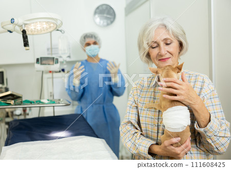 Smiling woman holding with bandaged belly after successful surgery Smiling woman holding with bandaged belly after successful surgery 111608425