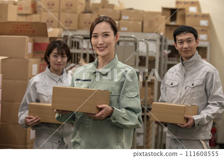 Three men and women in work clothes working in a distribution warehouse 111608555