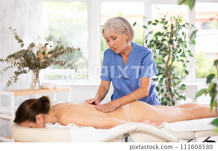 Unrecognizable young woman lies face down and enjoy shoulder massage for body care Unrecognizable young woman lies face down and enjoy shoulder massage for body care 111608580
