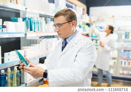 In pharmacy, male specialist holds and shows new effective remedy for moisturizing delicate skin In pharmacy, male specialist holds and shows new effective remedy for moisturizing delicate skin 111608718