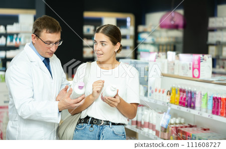 Male pharmacist gives advice to young woman on what lubricant to buy for personal hygiene Male pharmacist gives advice to young woman on what lubricant to buy for personal hygiene 111608727