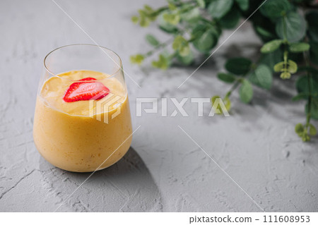 A glass of mango smoothie with strawberry A glass of mango smoothie with strawberry 111608953