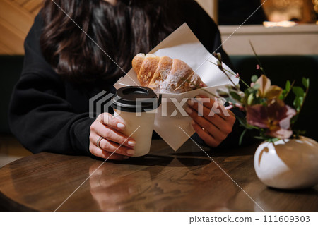 Woman holding a mug of coffee and a croissant Woman holding a mug of coffee and a croissant 111609303
