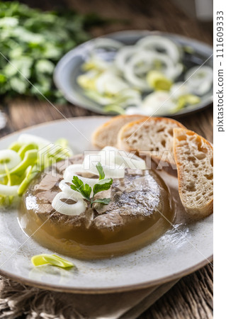 Homemade pork aspic, meat jelly with onion and leek in a white plate 111609333