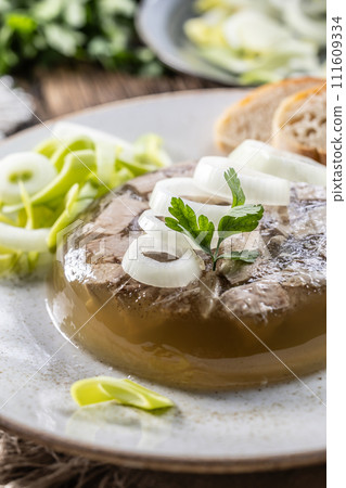 Homemade pork aspic, meat jelly with onion and leek in a white plate 111609334