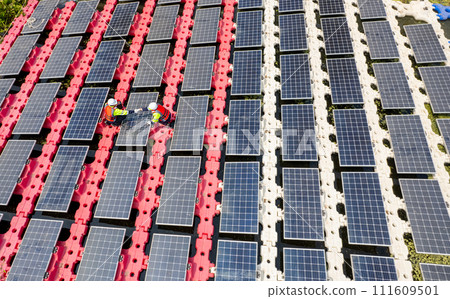Wide shot and top view of two technician workers check and maintenance solar cell panel over the water reservoir as solar farm factory. Wide shot and top view of two technician workers check and maintenance solar cell panel over the water reservoir as solar farm factory. 111609501