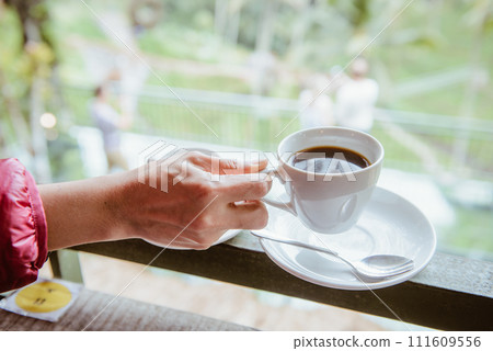 Woman hand holding a cup of hot Luwak coffee, one of the most expensive coffee in the world in the coffee shop in Bali, Indonesia. Woman hand holding a cup of hot Luwak coffee, one of the most expensive coffee in the world in the coffee shop in Bali, Indonesia. 111609556