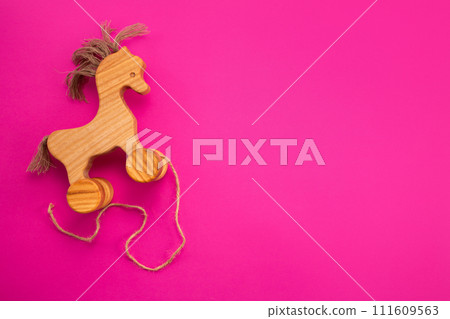 Wooden horse on pink background. Eco-friendly. Greeting card. Flat lay Wooden horse on pink background. Eco-friendly. Greeting card. Flat lay 111609563