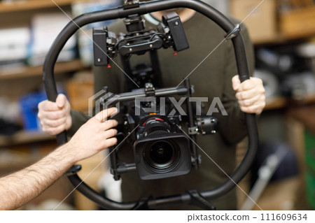 Professional videographer holding camera on gimbal rig steadycam to make video without shaking Professional videographer holding camera on gimbal rig steadycam to make video without shaking 111609634