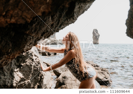 Woman summer travel sea. Happy tourist enjoy taking picture outdoors for memories. Woman traveler posing on the beach at sea surrounded by volcanic mountains, sharing travel adventure journey Woman summer travel sea. Happy tourist enjoy taking picture outdoors for memories. Woman traveler posing on the beach at sea surrounded by volcanic mountains, sharing travel adventure journey 111609644