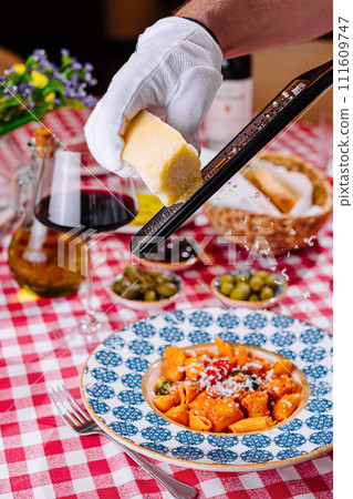 hef grates cheese to the plate with fresh penne pasta 111609747