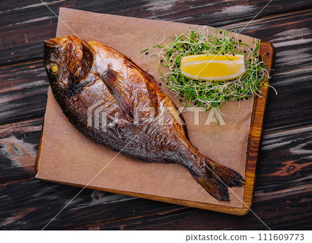 Board with fried dorado on wooden background 111609773