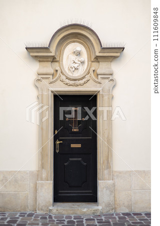A wooden black door with small window in an arched doorway A wooden black door with small window in an arched doorway 111609848