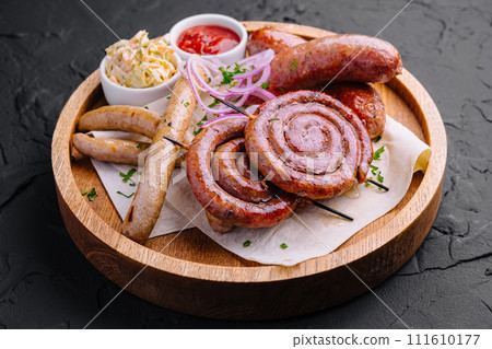 Grilled sausages on a wooden board with sauce 111610177