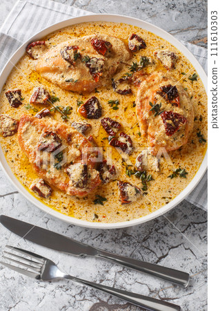 Marry Me Chicken with Creamy Garlic Sun Dried Tomato sauce closeup on the plate on the table. Vertical top view 111610303