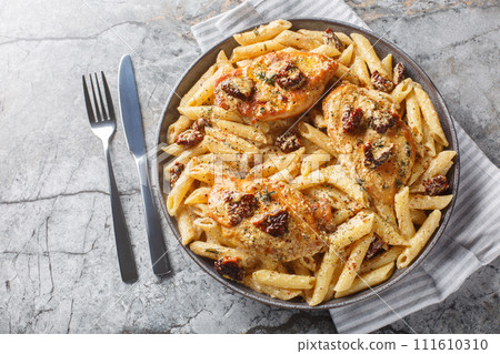 Creamy Marry Me Chicken pasta with sun-dried tomatoes, cheese, herbs and aromatic sauce close-up in a plate. Horizontal top view Creamy Marry Me Chicken pasta with sun-dried tomatoes, cheese, herbs and aromatic sauce close-up in a plate. Horizontal top view 111610310