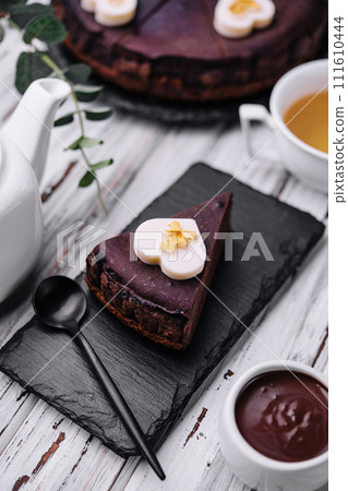 Sacher cake slice and tea on wood Sacher cake slice and tea on wood 111610444