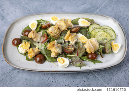 Warm salad with rapan (snails), tomatoes, cucumbers, leafy vegetables, quail eggs and olive oil. Traditional seafood salad. Close-up, selective focus. Warm salad with rapan (snails), tomatoes, cucumbers, leafy vegetables, quail eggs and olive oil. Traditional seafood salad. Close-up, selective focus. 111610750