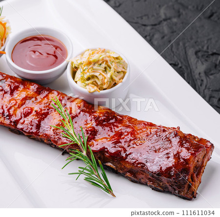 Grilled pork ribs in barbecue sauce and honey with sauerkraut on white plate Grilled pork ribs in barbecue sauce and honey with sauerkraut on white plate 111611034
