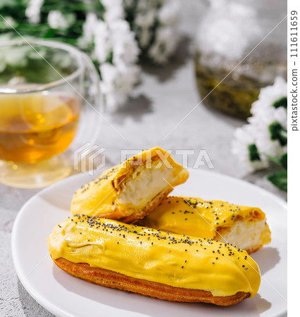 Fresh tasty eclair on white plate and cup of tea 111611659