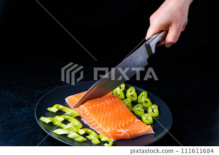 Raw salmon filet with rosemary and spices on plate, black stone background. Top view, flat lay 111611684