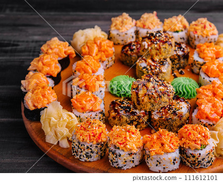 Tasty appetizing sushi rolls set on wooden board Tasty appetizing sushi rolls set on wooden board 111612101