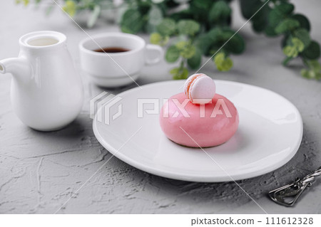 Pink mousse cake decorated with white macaroon and tea Pink mousse cake decorated with white macaroon and tea 111612328