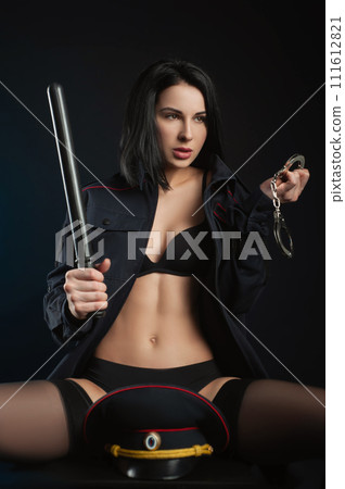 sexy girl in a military police uniform on a dark background with handcuffs and a rubber button, role-playing and striptease for adults 111612821