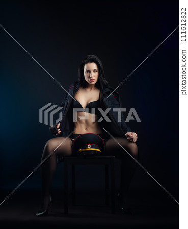 sexy girl in a military police uniform on a dark background with handcuffs and a rubber button, role-playing and striptease for adults 111612822