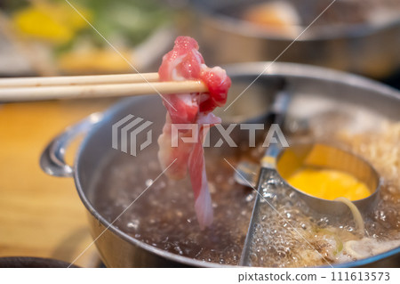 Chopstick holding sliced meat. hot pot with cheese fondue 111613573