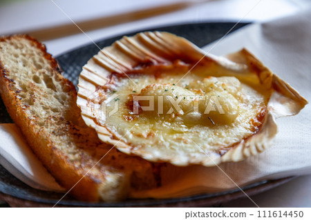 Lofoten Islands delicacy: Scallop in its shell, cheese gratinated, alongside crusty bread 111614450