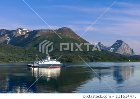 Ferry journey across calm fjord, verdant slopes and peaks under clear sky 111614473