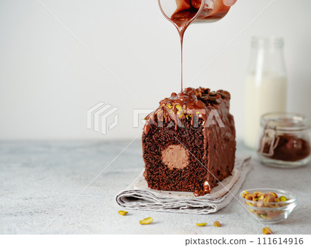 Travel Cake or Tube Cake or Voyage Cake filled center tube ganache pouring chocolate icing and pistachio. Chocolate loaf cake with chocolate cream-cheese filled center. Copy space. Travel Cake or Tube Cake or Voyage Cake filled center tube ganache pouring chocolate icing and pistachio. Chocolate loaf cake with chocolate cream-cheese filled center. Copy space. 111614916
