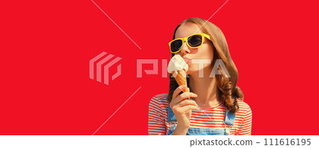 Summer portrait of happy young woman eating ice cream wearing sunglasses on red studio background Summer portrait of happy young woman eating ice cream wearing sunglasses on red studio background 111616195