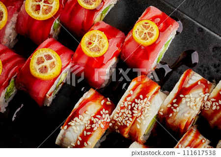 Vibrant sushi rolls with tuna, eel, kumquat and sesame on dark slate Vibrant sushi rolls with tuna, eel, kumquat and sesame on dark slate 111617538