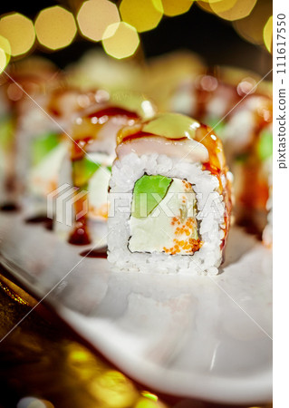 Sushi roll with scallop, cream cheese, tobiko and avocado in festive setting Sushi roll with scallop, cream cheese, tobiko and avocado in festive setting 111617550
