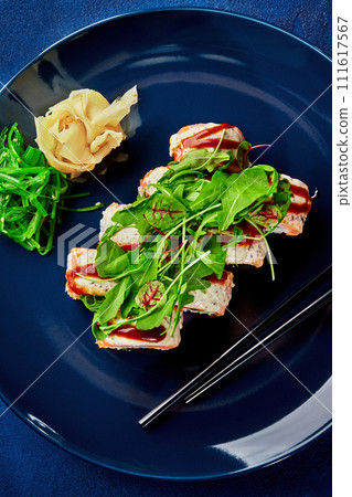 Gourmet sushi roll with salmon and greens on blue plate Gourmet sushi roll with salmon and greens on blue plate 111617567