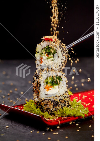 Sesame seeds sprinkling on vegetarian sushi roll tower 111617607