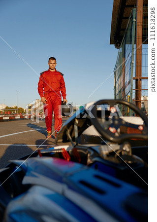 Confident go-kart driver walking to car before race at starting line 111618298