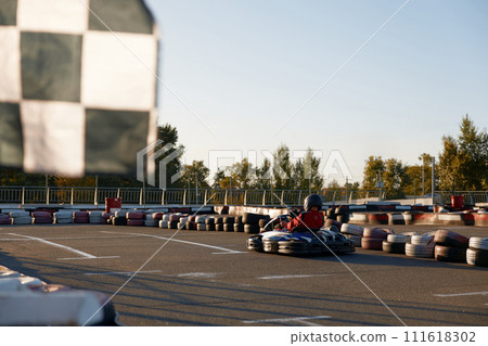 Go-cart racer moving fast on open air motor racing track 111618302