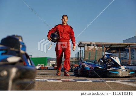 Go-kart driver walking to car before race at starting line 111618316