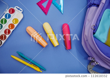 Backpack with colorful school supplies flat lay on blue background 111618332