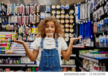 Portrait of funny school girl feeling confused standing at stationery store 111618390